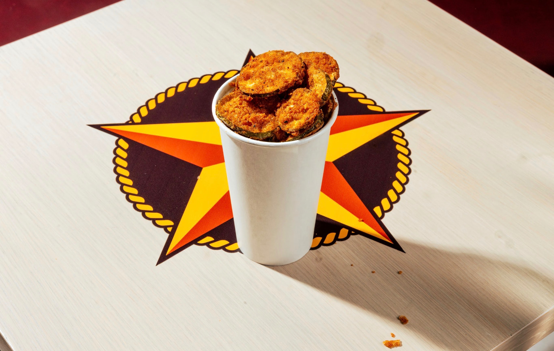 Cup of fried pickle chips on a Hotbirds star table